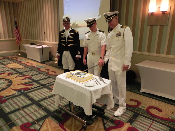 Cutting the traditional U.S. Navy birthday cake in October are Midshipman James Waters Jr., Navy ROTC (c), and Capt. Yancey Lindsey, USN, with supervision from Capt. Dave Grundies, USN (Ret.).